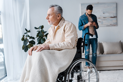 selective focus of disabled senior man in wheelchair near son