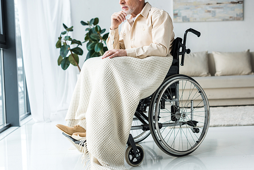 cropped view of pensive disabled senior man in wheelchair at home