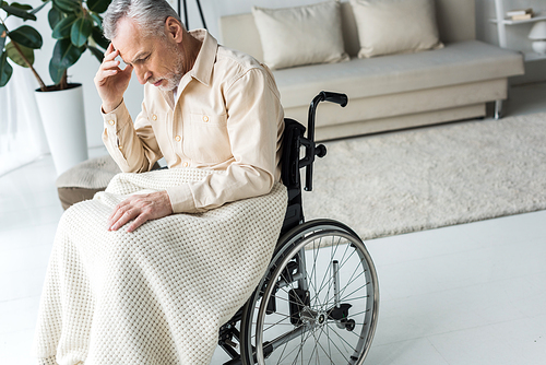 pensive disabled senior man sitting in wheelchair at home