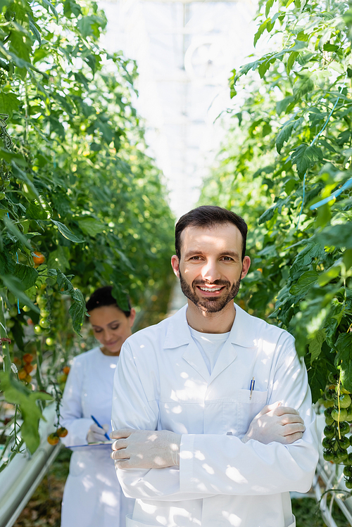 smiling agricultural technologist  near african american colleague working on blurred background