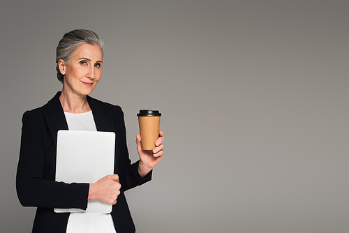 Middle aged businesswoman with coffee to go and laptop isolated on grey