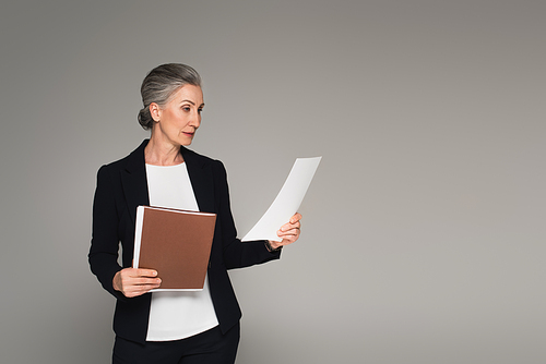 Businesswoman holding document and paper folder isolated on grey