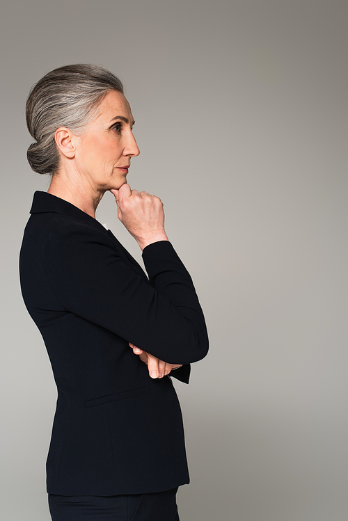 Side view of pensive mature businesswoman looking away isolated on grey