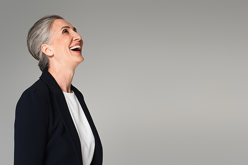 Mature businesswoman in formal wear laughing isolated on grey