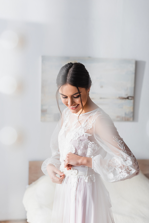smiling, brunette bride in white wedding dress on blurred foreground