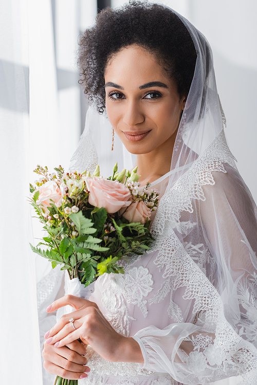 pretty african american bride holding wedding bouquet while 
