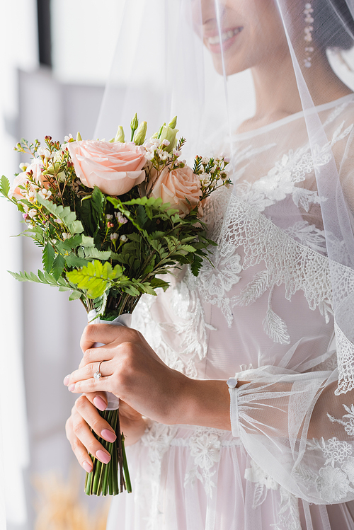 cropped view of african american bride in veil holding wedding bouquet