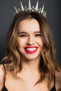 positive young woman in tiara with diamonds on grey