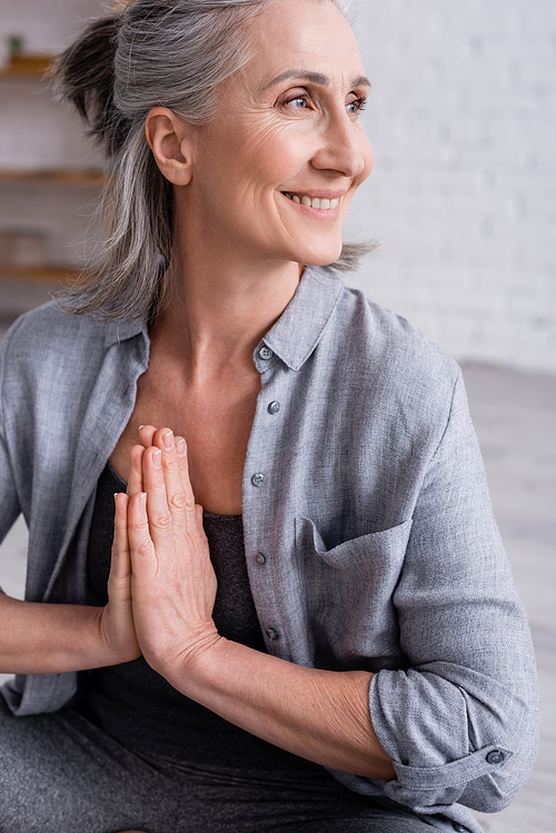 happy mature woman with grey hair and praying hands