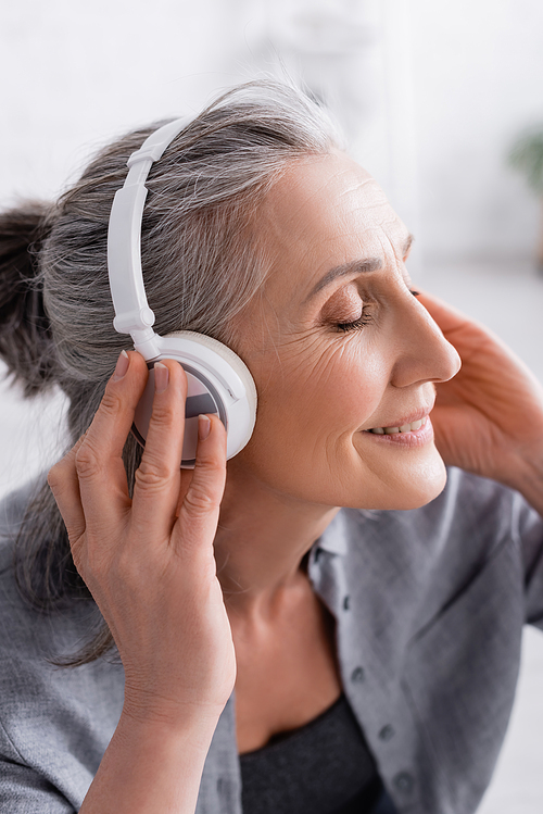 happy middle aged woman listening music in in wireless headphones