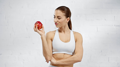 Brunette sportswoman looking at juicy apple