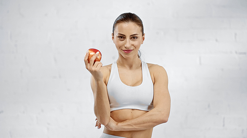 Smiling sportswoman holding fresh apple