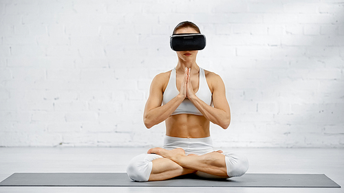 Young woman in vr headset sitting in yoga pose
