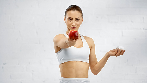 Sportswoman holding marshmallow and blurred apple