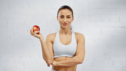 Smiling sportswoman holding organic apple