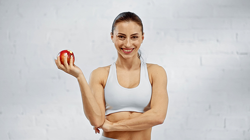Positive sportswoman holding apple and 