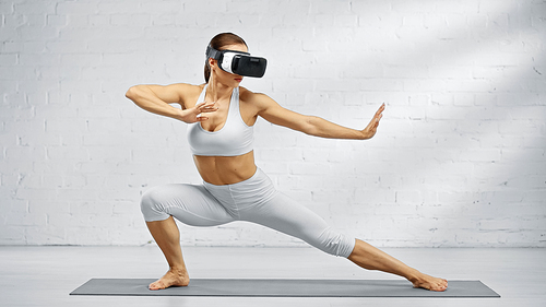 Fit woman using virtual reality headset on yoga mat