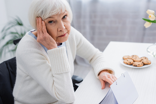 aged woman, sick on dementia, touching head while  near calendar