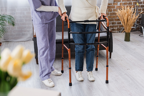 partial view of nurse assisting senior woman during rehabilitation with medical walkers at home