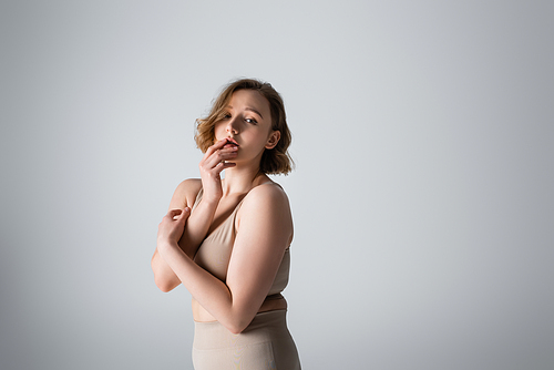 overweight young woman in underwear posing on grey