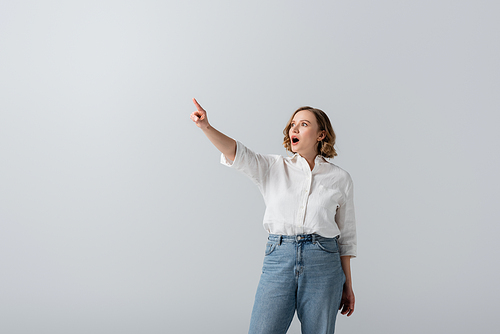 overweight and shocked woman in white shirt pointing with finger isolated on grey