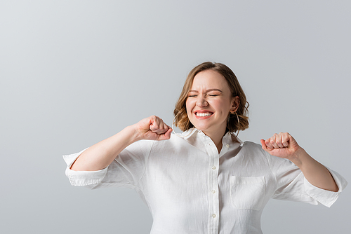 pleased overweight woman in white shirt celebrating isolated on grey