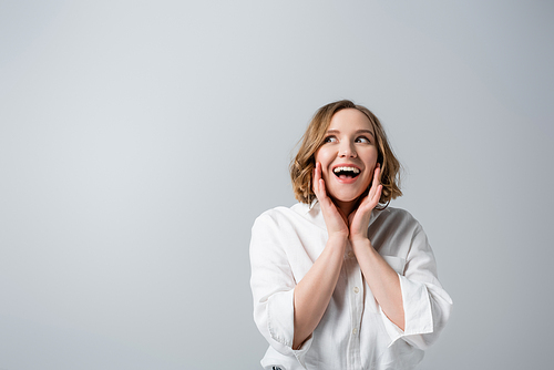 excited overweight woman in white shirt isolated on grey