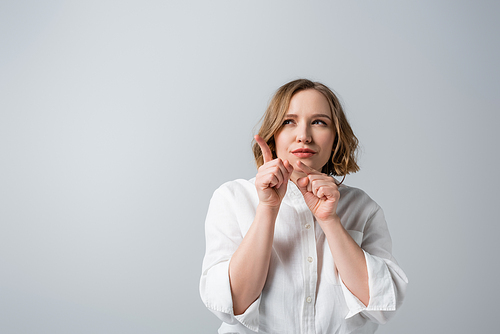 curious overweight woman in white shirt pointing with fingers isolated on grey