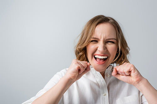 excited overweight woman in white shirt celebrating isolated on grey