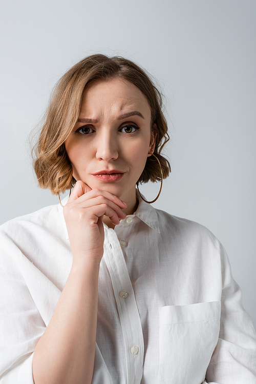 pensive overweight woman in white shirt isolated on grey