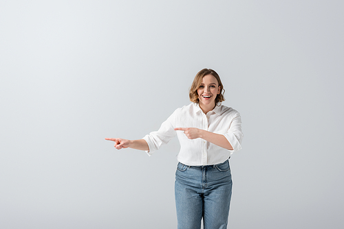 happy overweight woman in jeans pointing with fingers isolated on grey