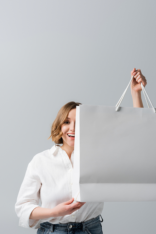 happy overweight woman in white shirt holding shopping bag on grey