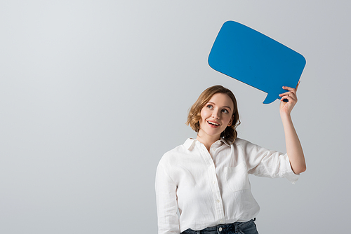 smiling overweight woman in white shirt holding blue speech bubble isolated on grey