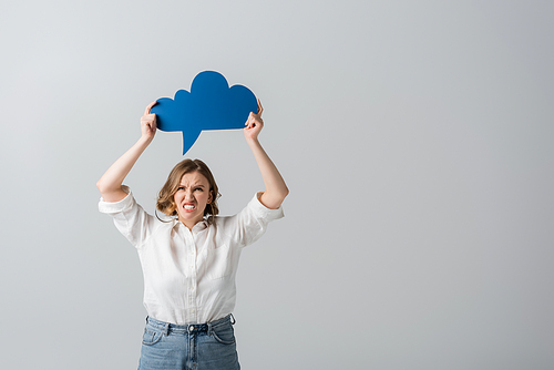 angry overweight woman in white shirt holding blue thought bubble above head isolated on grey