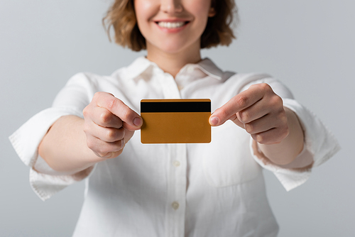 cropped view of happy plus size woman holding credit card isolated on grey