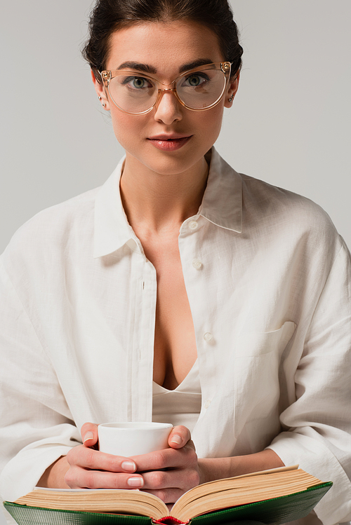 young woman in glasses with book holding cup of coffee isolated on white