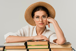 young woman in sun hat leaning on pile of books isolated on white