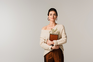 young woman holding book with wildflowers isolated on grey