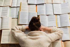 top view of tired woman sleeping near open books