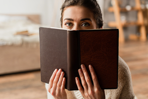 woman obscuring face while holding book and 