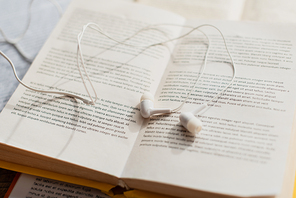 close up of white earphones on blurred books