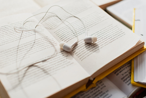 white earphones on stack of blurred books