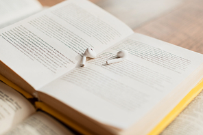 white and wireless earphones on blurred book