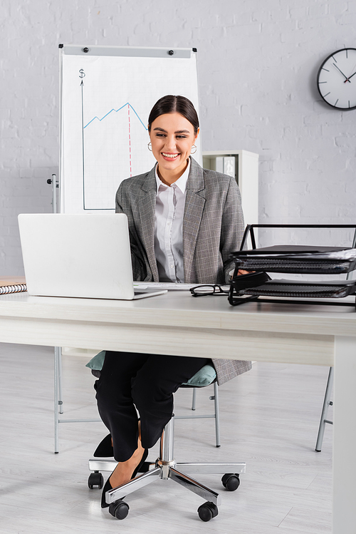 Cheerful businesswoman looking at laptop on working table