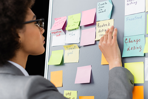 Blurred african american businesswoman looking at sticky notes