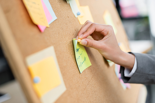 Cropped view of businesswoman attaching sticky note on board