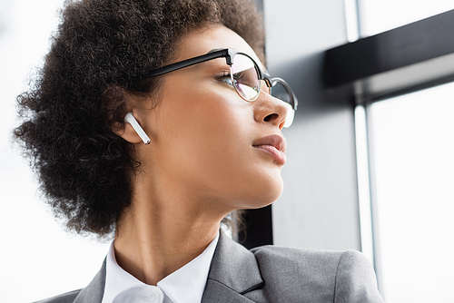 Low angle view of african american businesswoman in earphone looking at window