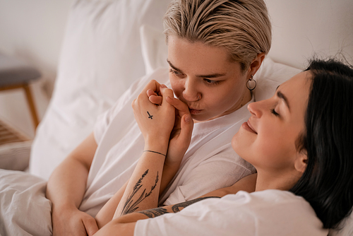 young lesbian couple lying in bed and holding hands