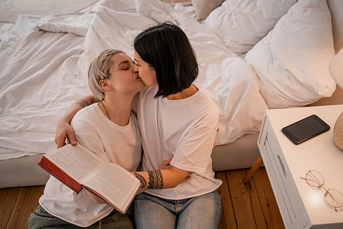 high angle view of young lesbian couple kissing in bedroom