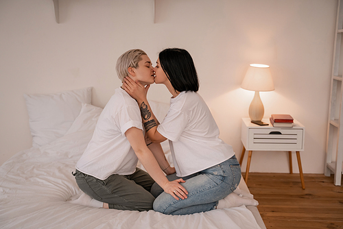 side view of lesbian couple kissing on bed